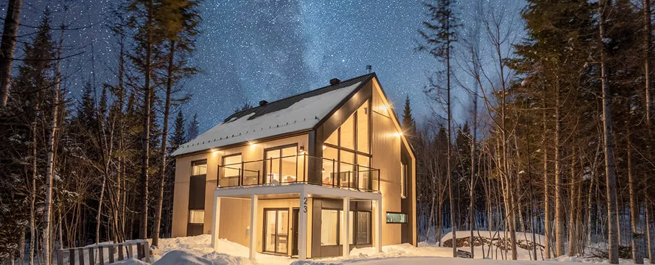 Chalet tout vitré et bien éclairé, en pleine forêt, la nuit